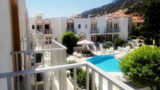 Hotellanläggning med en pool och solstolar omgiven av gröna växter. (AI-genererad text)