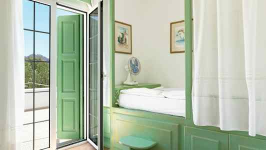 Ett rum med gröna möbler och en dörr som leder till en balkong. (AI-genererad text)