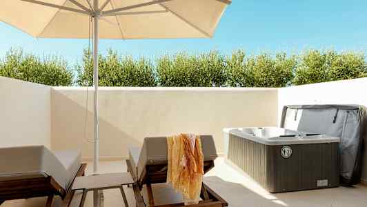 Utomhusmiljö med solstolar, parasoll och en bubbelpool. (AI-genererad text)