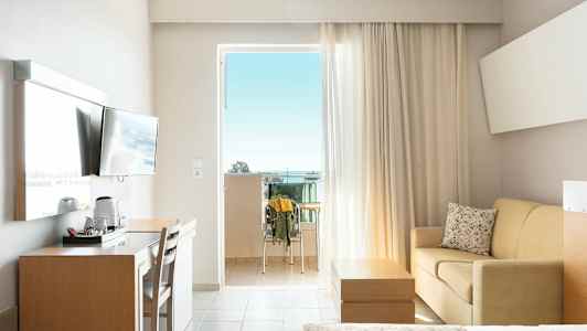 Hotellrum med balkong, TV, skrivbord, soffa och säng. (AI-genererad text)