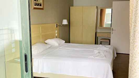 Bild av ett hotellrum med två enkelsängar med vita sängkläder, en garderob och en spegel. (AI-genererad text)