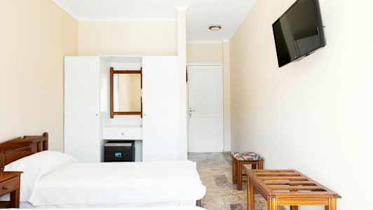 En hotellrumsinteriör med två enkelsängar, en byrå med spegel, och en väggmonterad TV. (AI-genererad text)