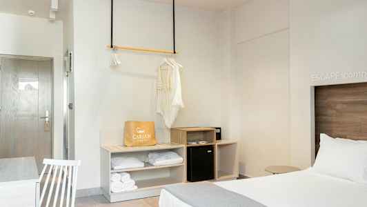 Ett hotellrum med en bäddad säng, en garderobsutrymme och ett bord med en stol. (AI-genererad text)