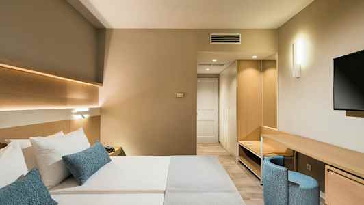 Modernt hotellrum med dubbelsäng, skrivbord och TV. (AI-genererad text)