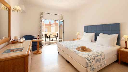 Hotellrum med dubbelsäng, sittplats, fönster och möblerad terrass. (AI-genererad text)