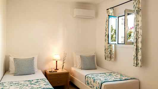 Rum med två enkelsängar och ett nattduksbord med lampa. (AI-genererad text)