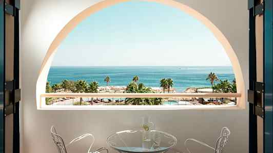 Utsikt från en balkong med havet, palmer och en pool i bakgrunden. (AI-genererad text)