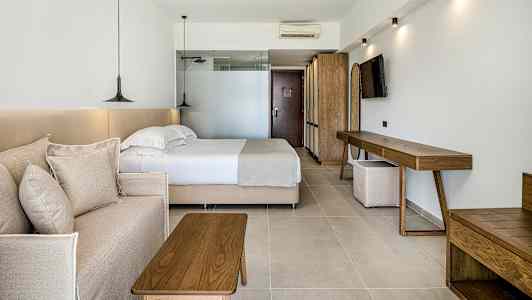 Ett hotellrum med en säng, en soffa och trämöbler. (AI-genererad text)