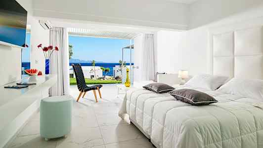 Ljus sovrumsinteriör med utsikt över havet genom öppna glasdörrar. (AI-genererad text)