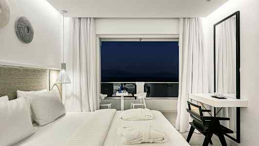 Modernt hotellrum med stor säng och utgång till balkong. (AI-genererad text)