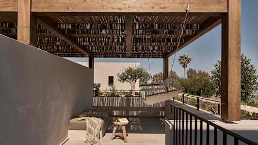 En utomhusterrass med en träpergola, en hängmatta och ett sittområde med bord. (AI-genererad text)