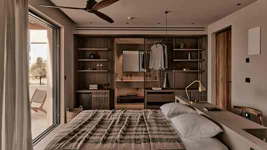 Ett varmt inrett sovrum med dubbelsäng, trädetaljer och en bred balkongdörr. (AI-genererad text)