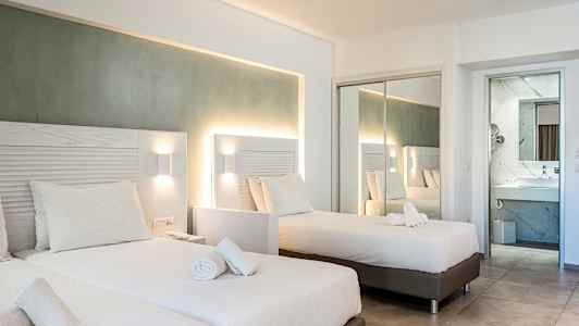 Ett hotellrum med två enkelsängar och en spegelvägg som reflekterar rummet. (AI-genererad text)