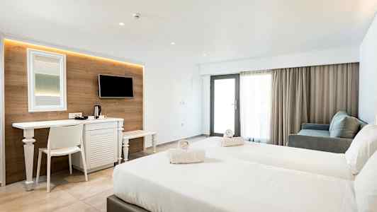 Ett hotellrum med två sängar, ett skrivbord, TV, och sittgrupp. (AI-genererad text)