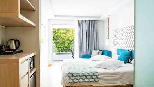 Bild av ett ljust hotellrum med säng, soffa och fönster med utsikt. (AI-genererad text)