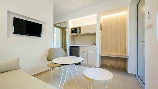 Ett modernt hotellrum med en liten sittgrupp och pentry. (AI-genererad text)