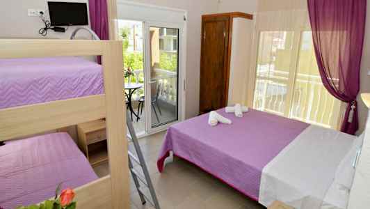 Ett rum med våningssäng och dubbelsäng, samt utgång till balkong. (AI-genererad text)