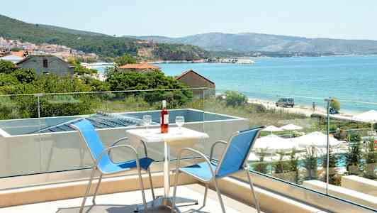 Två stolar och ett bord med en vinflaska på en terrass med utsikt mot havet. (AI-genererad text)