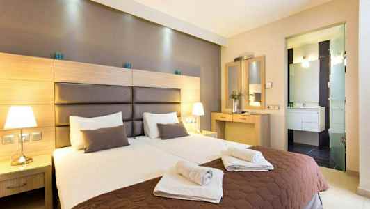 Två bäddade enkelsängar i ett hotellrum med nattduksbord och spegel. (AI-genererad text)