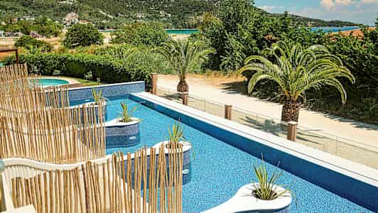 Pool med blått vatten, växtdekorationer och omgivande grönska. (AI-genererad text)