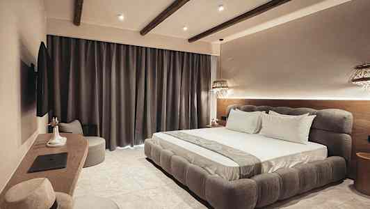 Ett modernt dubbelrum med stor säng, mörka gardiner och diskret belysning. (AI-genererad text)