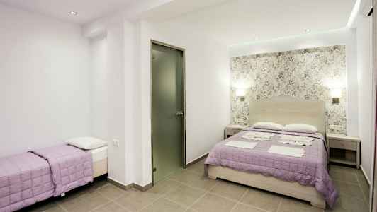 Ett sovrum med en dubbelsäng och en enkelbädd med lila överkast. (AI-genererad text)