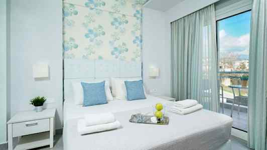 Modernt inrett sovrum med dubbelsäng, blommönstrad väggdekoration och glasdörr mot balkong. (AI-genererad text)