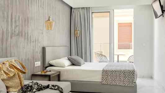 Modernt hotellrum med säng, soffa och balkongdörr. (AI-genererad text)