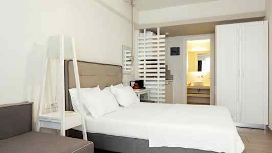 Ett modernt hotellrum med en dubbelsäng, en garderob och en synlig del av badrummet. (AI-genererad text)