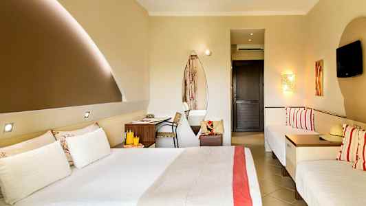 Ett hotellrum med en dubbelsäng, två enkelsängar, ett skrivbord, och en väggmonterad TV. (AI-genererad text)