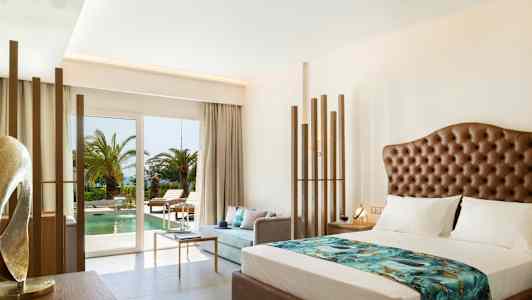 Ett hotellrum med modern inredning, utsikt över en pool och palmer utanför. (AI-genererad text)