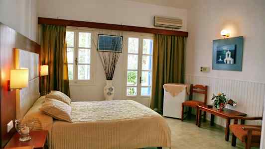 Hotellrum med säng, bord och stolar, fönster med gardiner. (AI-genererad text)