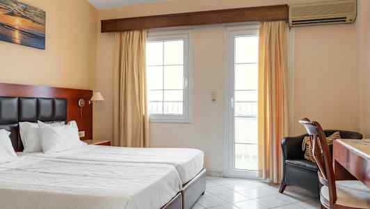 Hotellrum med två enkelsängar, skrivbord och fönster med ljusa gardiner. (AI-genererad text)