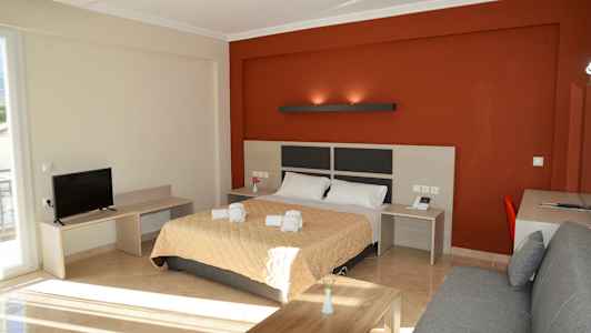 Ett rum med en säng, ett skrivbord, en soffa och en TV. (AI-genererad text)