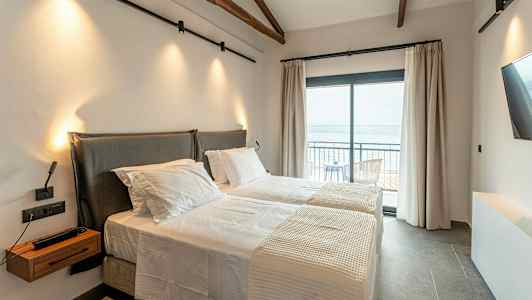 Ett hotellrum med två enkelsängar och en balkong med havsutsikt. (AI-genererad text)