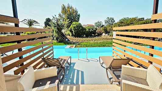 Två solstolar vid kanten av en swimmingpool med utsikt över en grön trädgård. (AI-genererad text)