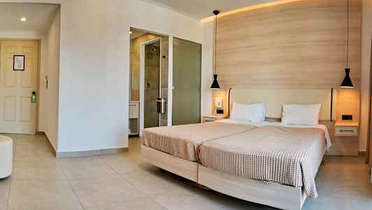 Ett hotellrum med två enkelsängar och en angränsande badrumsdörr. (AI-genererad text)