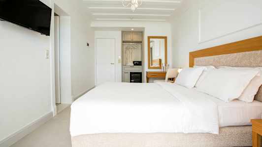 Modernt hotellrum med en bred säng, vit inredning och trädetaljer. (AI-genererad text)