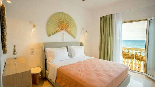 Sovrum med en dubbelsäng, dekorerat med en stor solfjäder på väggen och en balkong med utsikt över havet. (AI-genererad text)