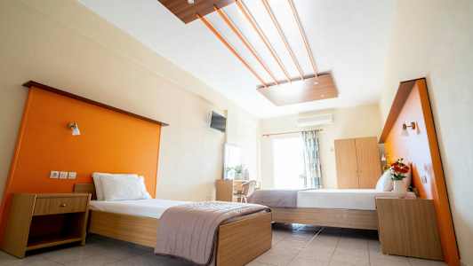 Ett hotellrum med två enkelsängar, orange väggpaneler och träinredning. (AI-genererad text)