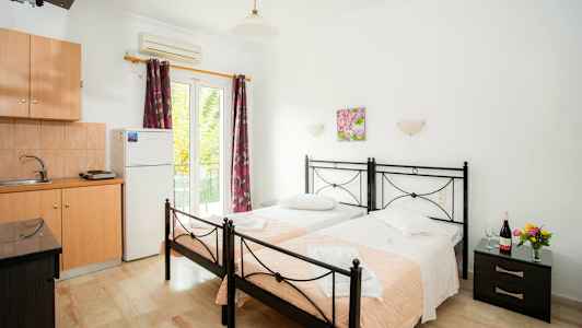 Två enkelsängar med rosa täcken i ett rum med köksutrustning. (AI-genererad text)