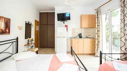 Ett ljus och luftigt sovrum med dubbelsängar, en liten köksdel och tillgång till en balkong. (AI-genererad text)