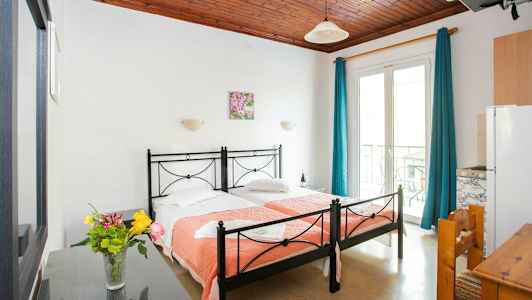 Ett hotellrum med två enkelsängar och en vas med blommor på ett bord. (AI-genererad text)