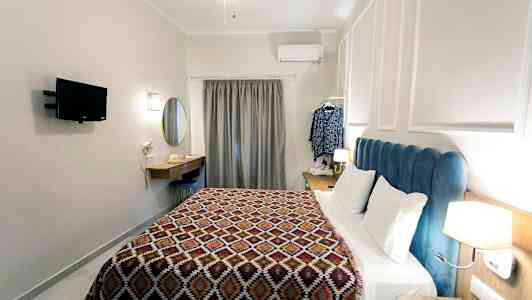 Ett hotellrum med en säng, väggmonterad TV, skrivbord och en gardin vid fönstret. (AI-genererad text)