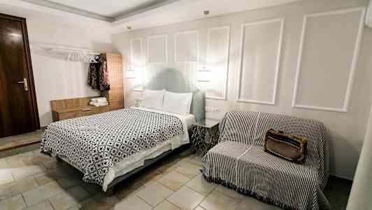 Ett hotellrum med en säng, ett soffliknande sittmöblemang och en garderob. (AI-genererad text)