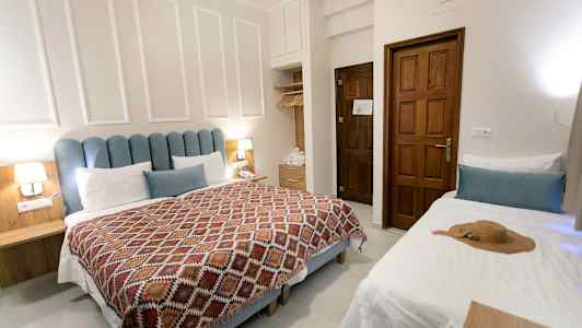 Ett hotellrum med en dubbelsäng, en enkelbädd och träinredning. (AI-genererad text)