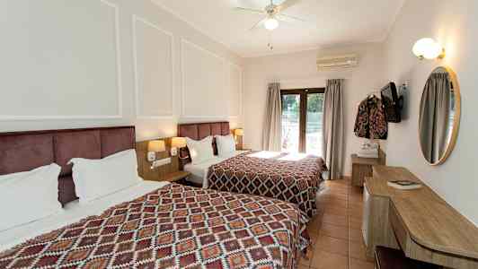 Hotellrum med två sängar och ett skrivbord, dekorerat med geometriska mönstrade överkast. (AI-genererad text)