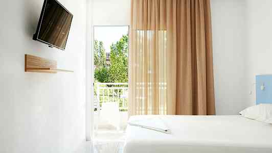 Ett ljust rum med en säng, en väggmonterad TV, och en balkong med utsikt. (AI-genererad text)