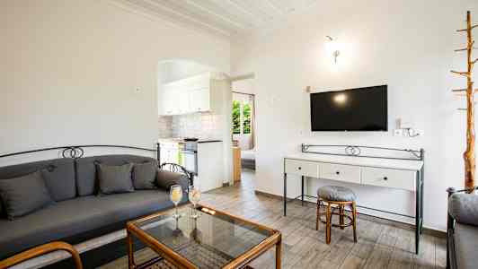 Vardagsrum med soffa, glasbord och en TV på väggen. (AI-genererad text)