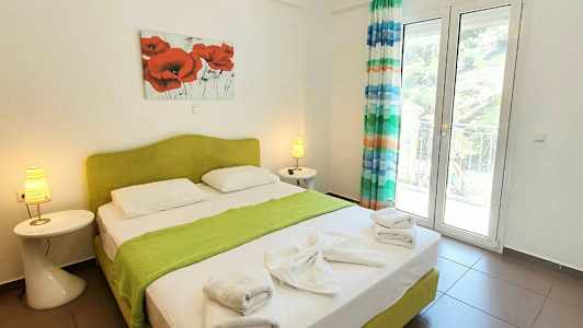 Ett sovrum med en dubbelsäng, grönt sängöverdrag, handdukar och dekorationer. (AI-genererad text)